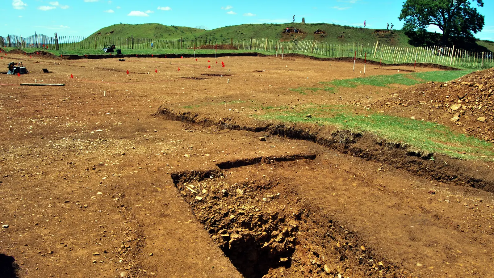 Excavated trenches cut into red soil on a levelled site