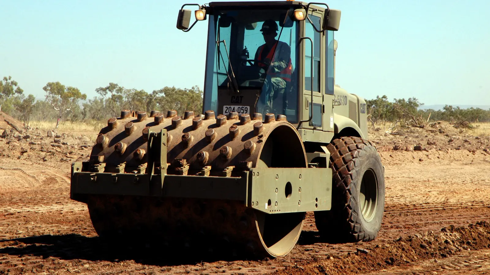 A compactor roller passing over a layer of fill