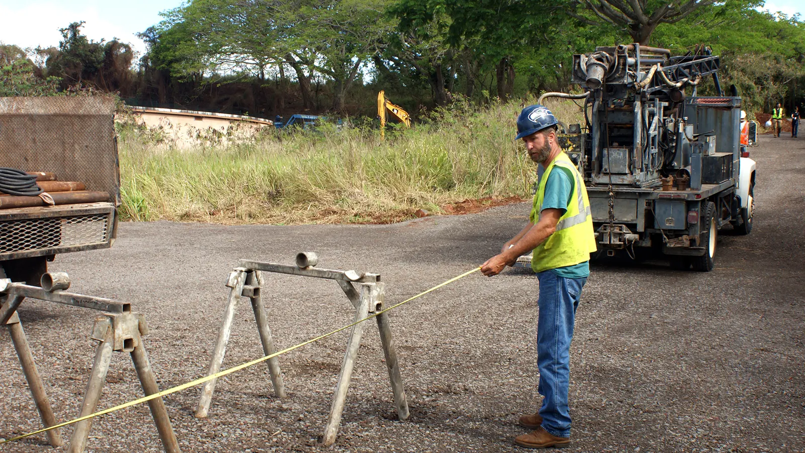 A worker measuring beside a drilling rig on a prepared site