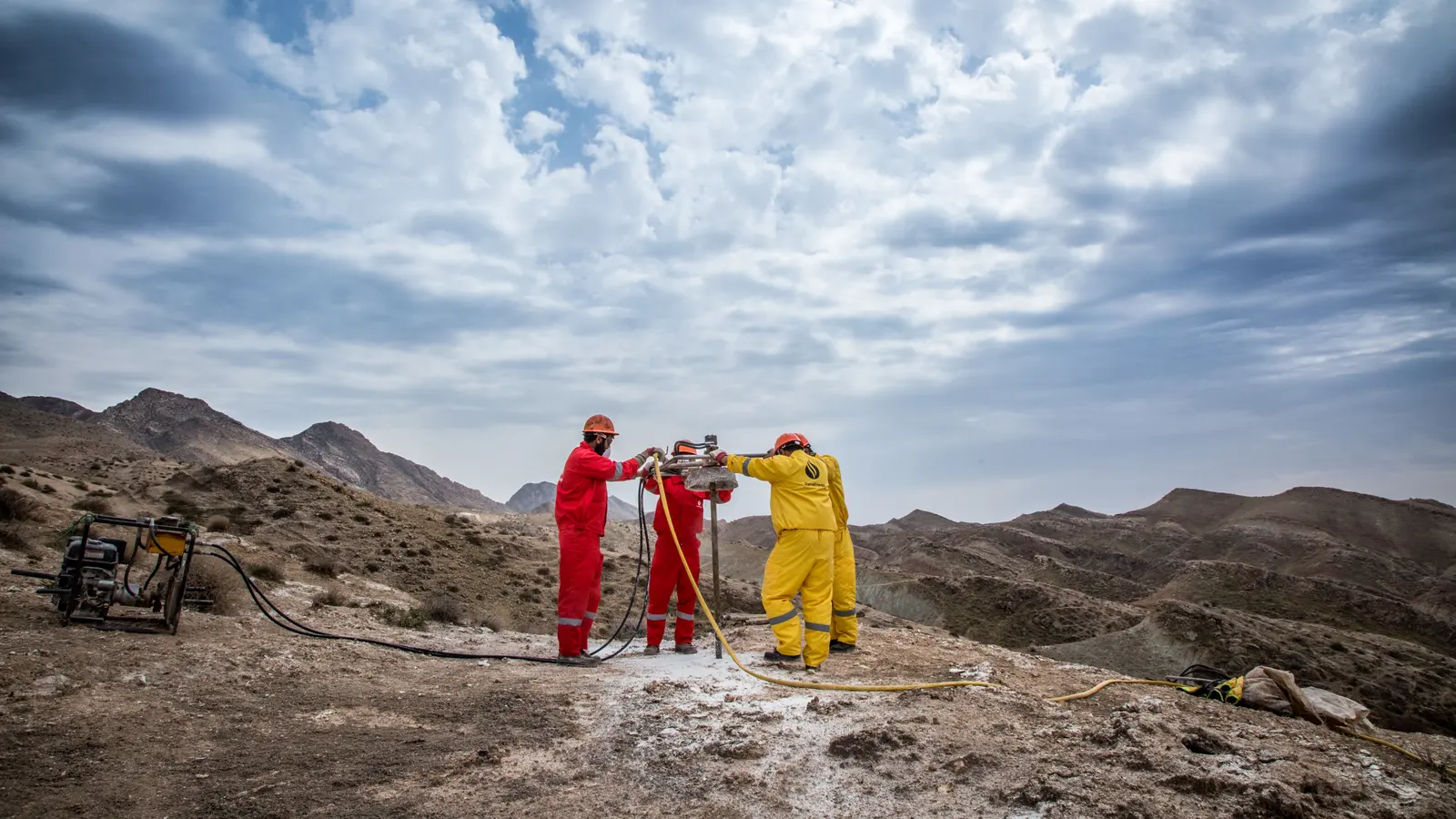 A drilling crew at a geotechnical rig in a dry mountain landscape