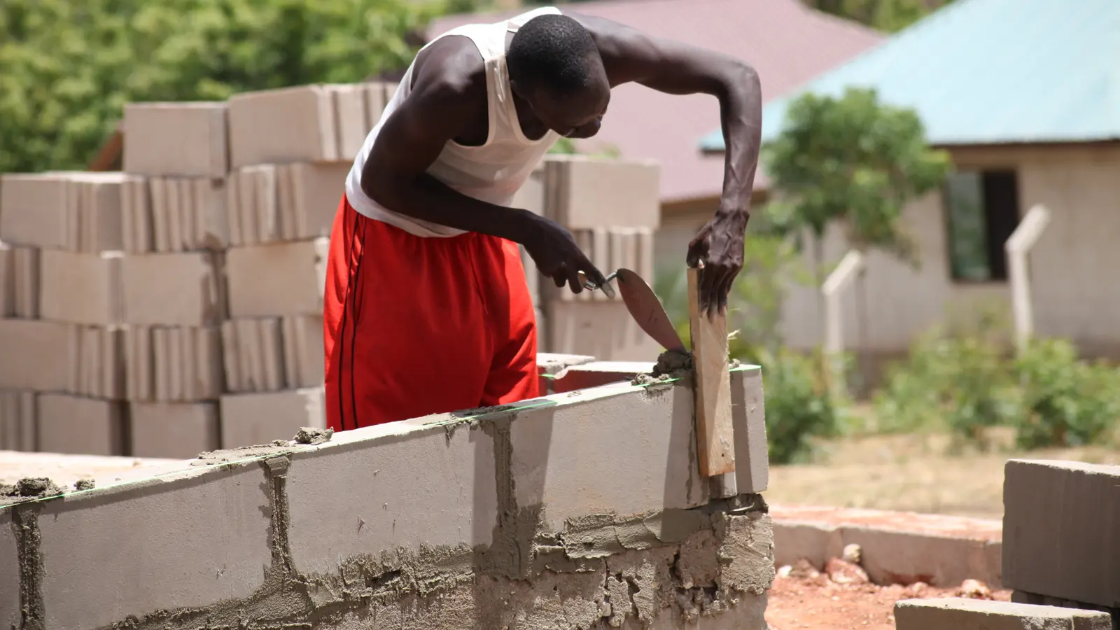 A mason laying concrete blocks on a wall