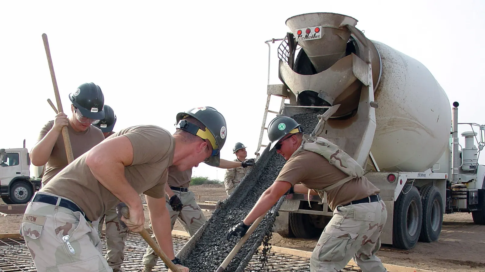 A construction crew placing concrete from a truck mixer onto reinforced formwork in Djibouti