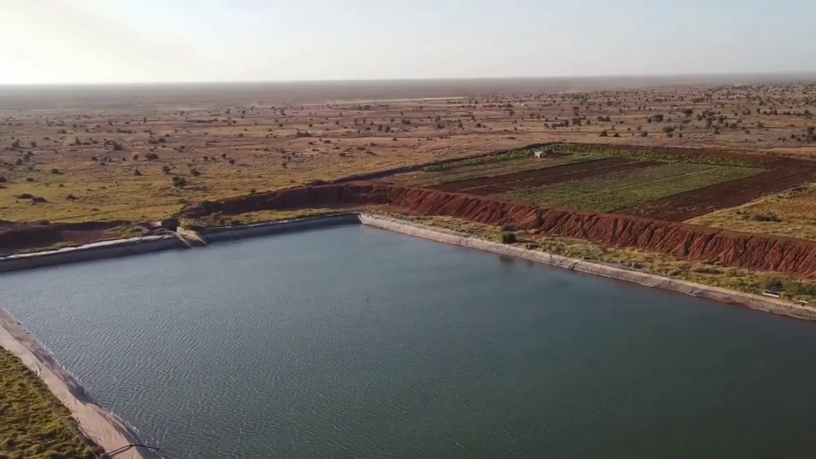 A lined water reservoir at Salahley, Somaliland, with farmland behind it