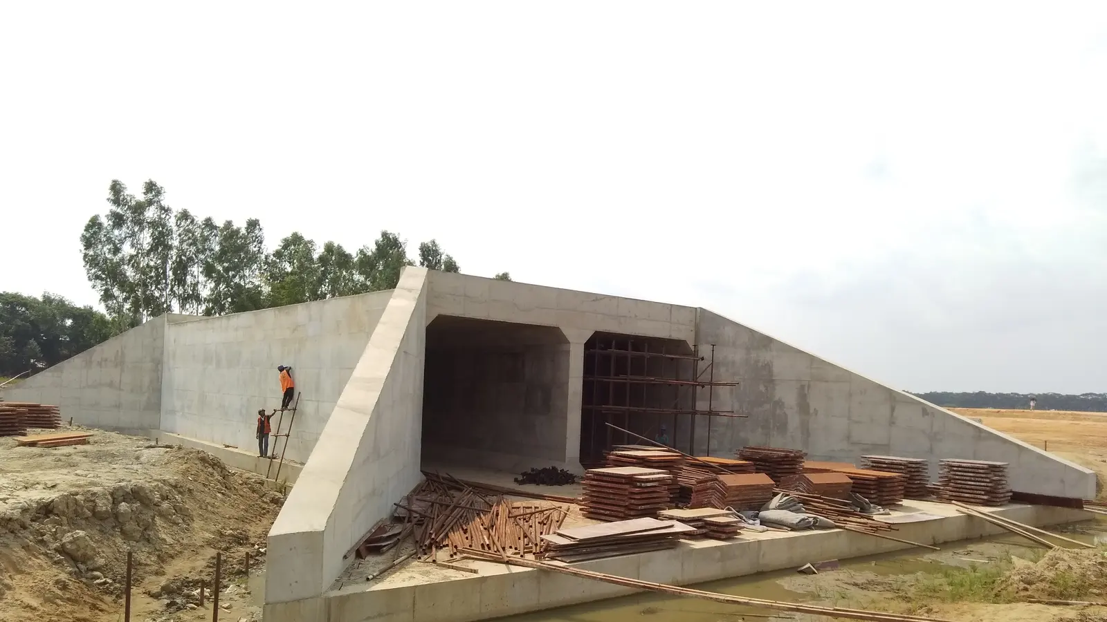 A reinforced concrete box culvert under construction with a worker on top