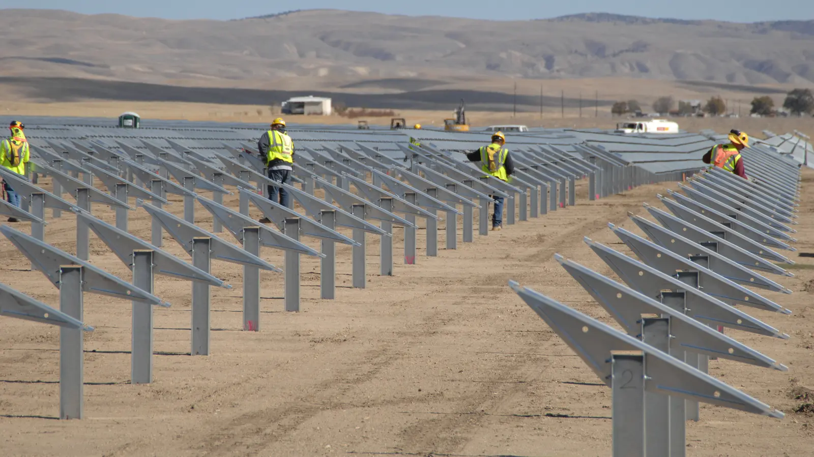 Crews working along rows of ground-mounted solar panels at a utility-scale plant (Topaz Solar Farm, California; illustrative)