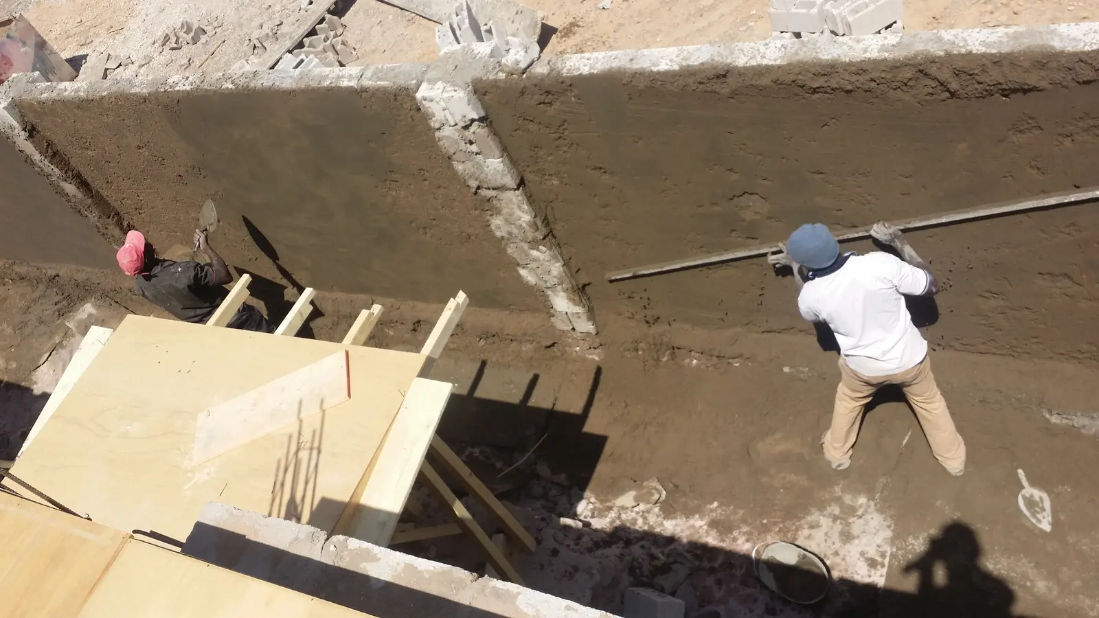 A worker checking a wall with a straight edge on a building site in Hargeisa
