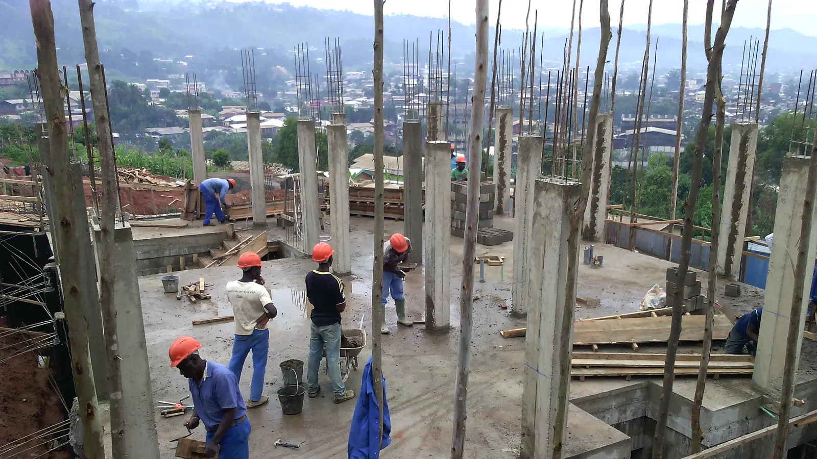 Workers on a slab fixing timber formwork around reinforced concrete columns