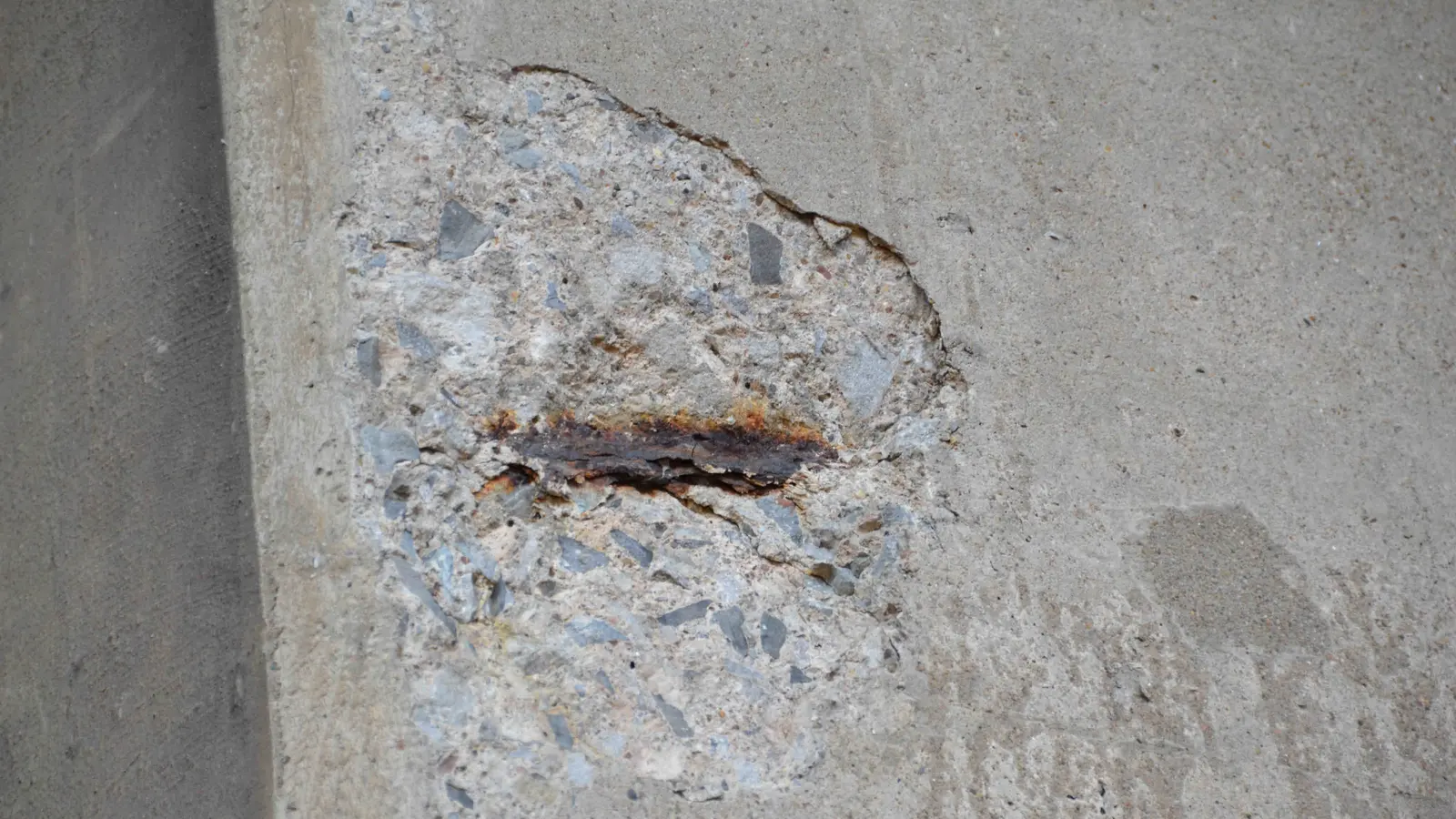 Spalled concrete on a bridge exposing rusted reinforcement