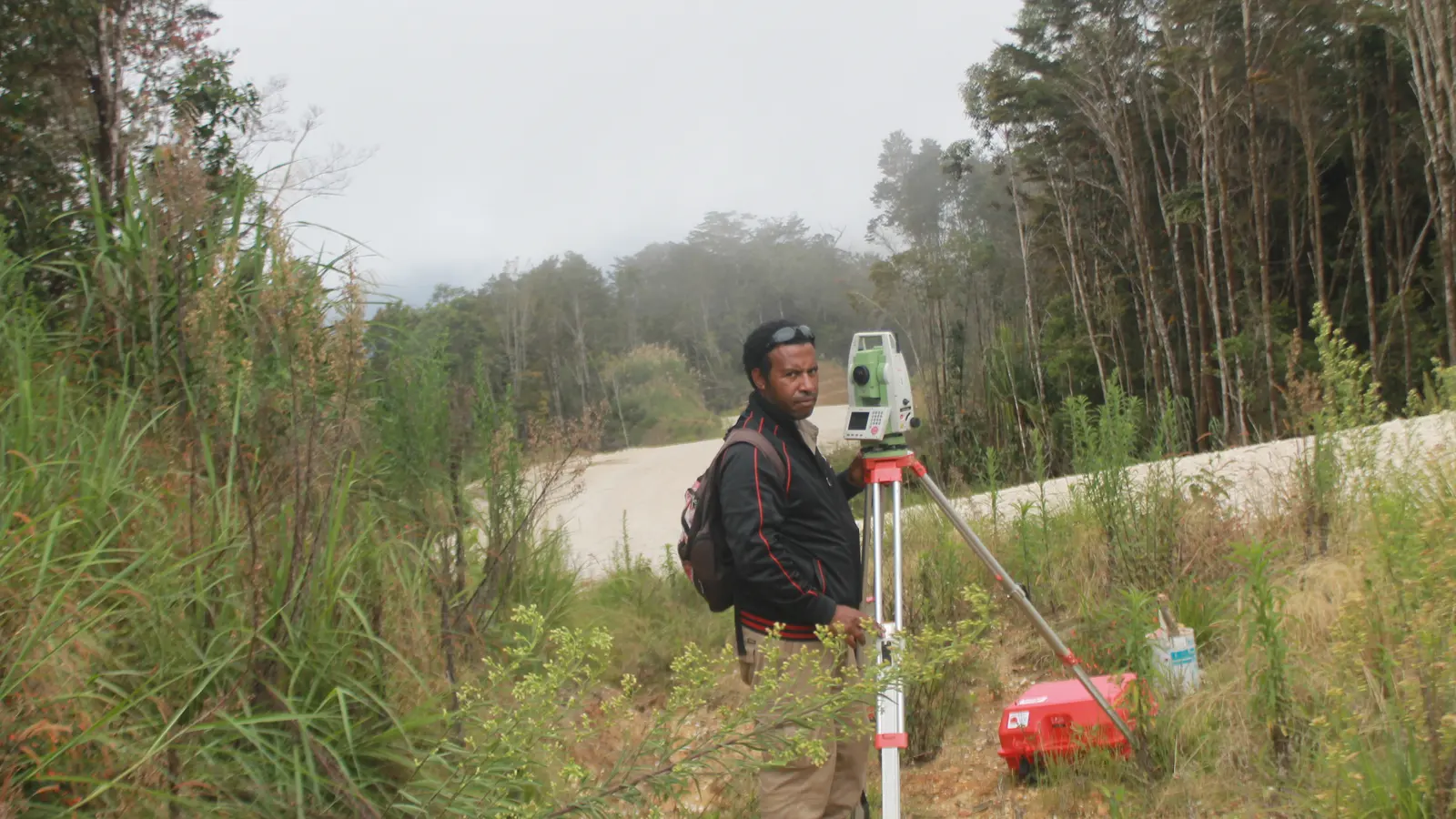 A surveyor working with a total station beside a road