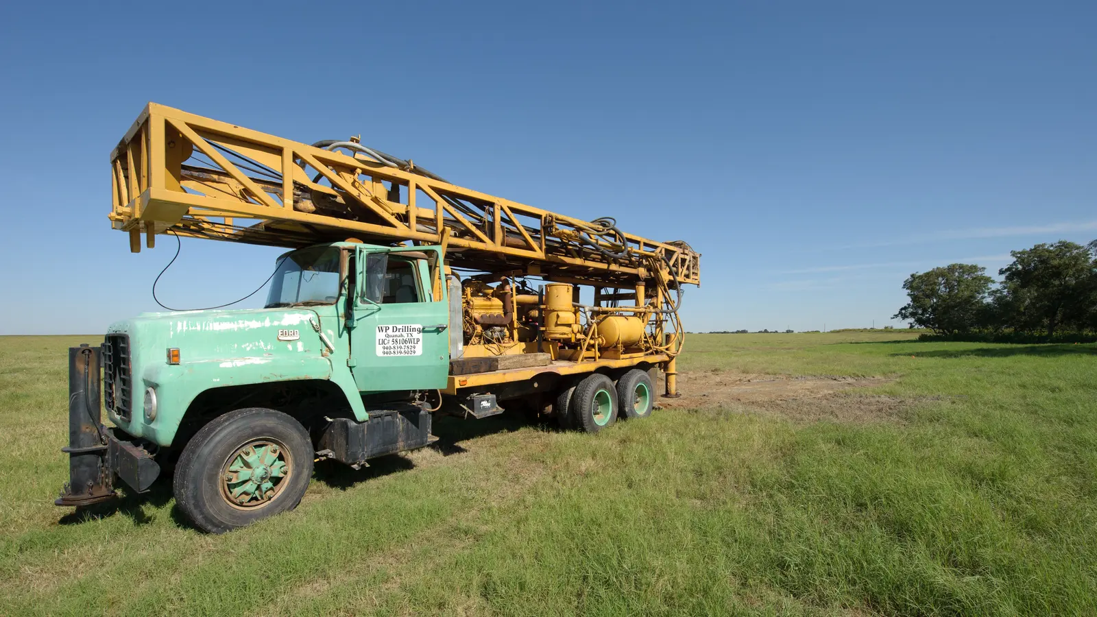 A truck-mounted drilling rig set up in an open field