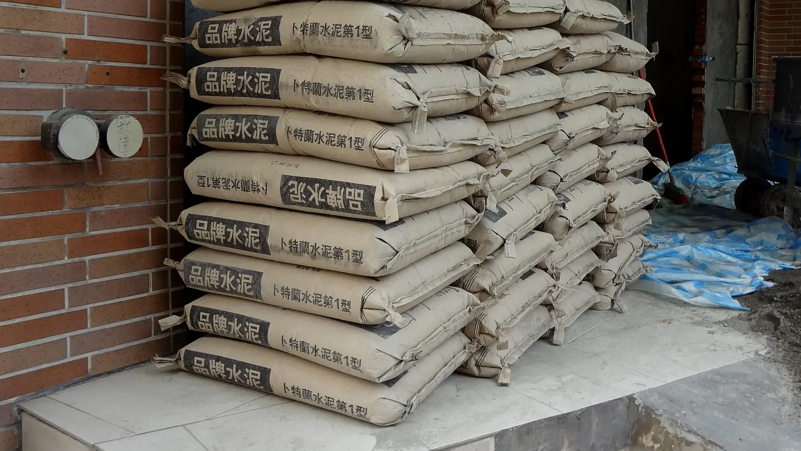 Stacked paper bags of Portland cement against a wall